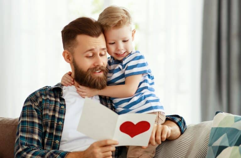 Little boy giving greeting card to dad