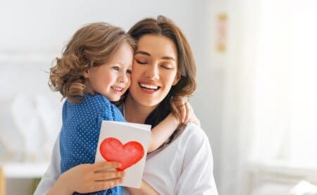Mother and daughter reading happy birthday greeting card