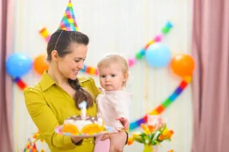 Mother showing baby first birthday cake